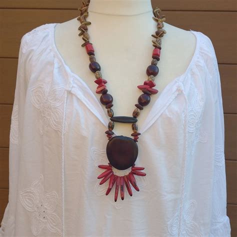 Un collier ethnique artisanal composé de graines, de bois et d'une perle centrale en ambre résine, évoquant la richesse des terres africaines.