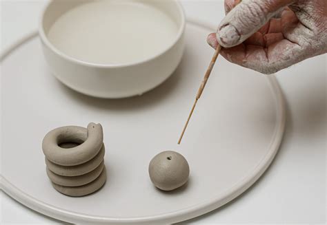 Un artiste modelant une petite figurine avec de l'argile autodurcissante sur une table propre