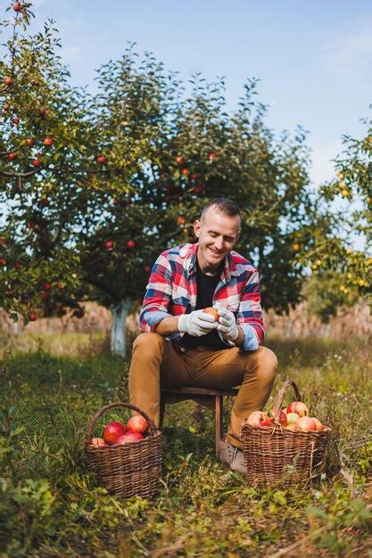Une photo de Tom Monnat souriant, dans un verger avec des pommiers