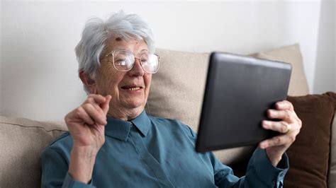 personne âgée utilisant une tablette dans un jardin fleuri