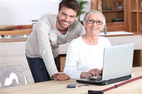 professeur d'informatique aidant une personne âgée sur un ordinateur portable