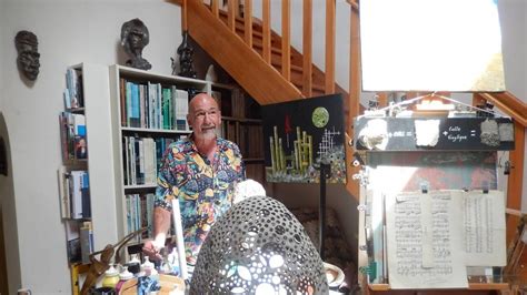 Portrait de l'artiste Didier Noisetier dans son atelier entouré de ses créations en verre